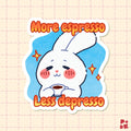 A die-cut sticker featuring a cute white cartoon bunny holding a cup of coffee, with the text 'More espresso Less depresso' in orange lettering on a light blue background. The sticker is shown on a pale pink grid paper background.