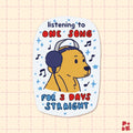 A die-cut sticker featuring a cartoon bear wearing headphones and a baseball cap, surrounded by musical notes and stars. The text reads 'listening to ONE SONG FOR 3 DAYS STRAIGHT' in blue and red lettering.