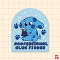 A die-cut sticker featuring a cute blue cartoon puppy holding a magnifying glass, surrounded by paw prints and stars on a light blue arched background. The text 'PROFESSIONAL CLUE FINDER' is printed at the bottom.