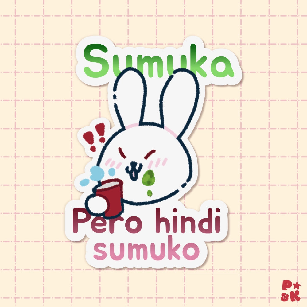 A die-cut sticker featuring a cute cartoon rabbit holding a red cup, with the text 'Sumuka' at the top and 'Pero hindi sumuko' at the bottom, shown on a pale pink grid background.