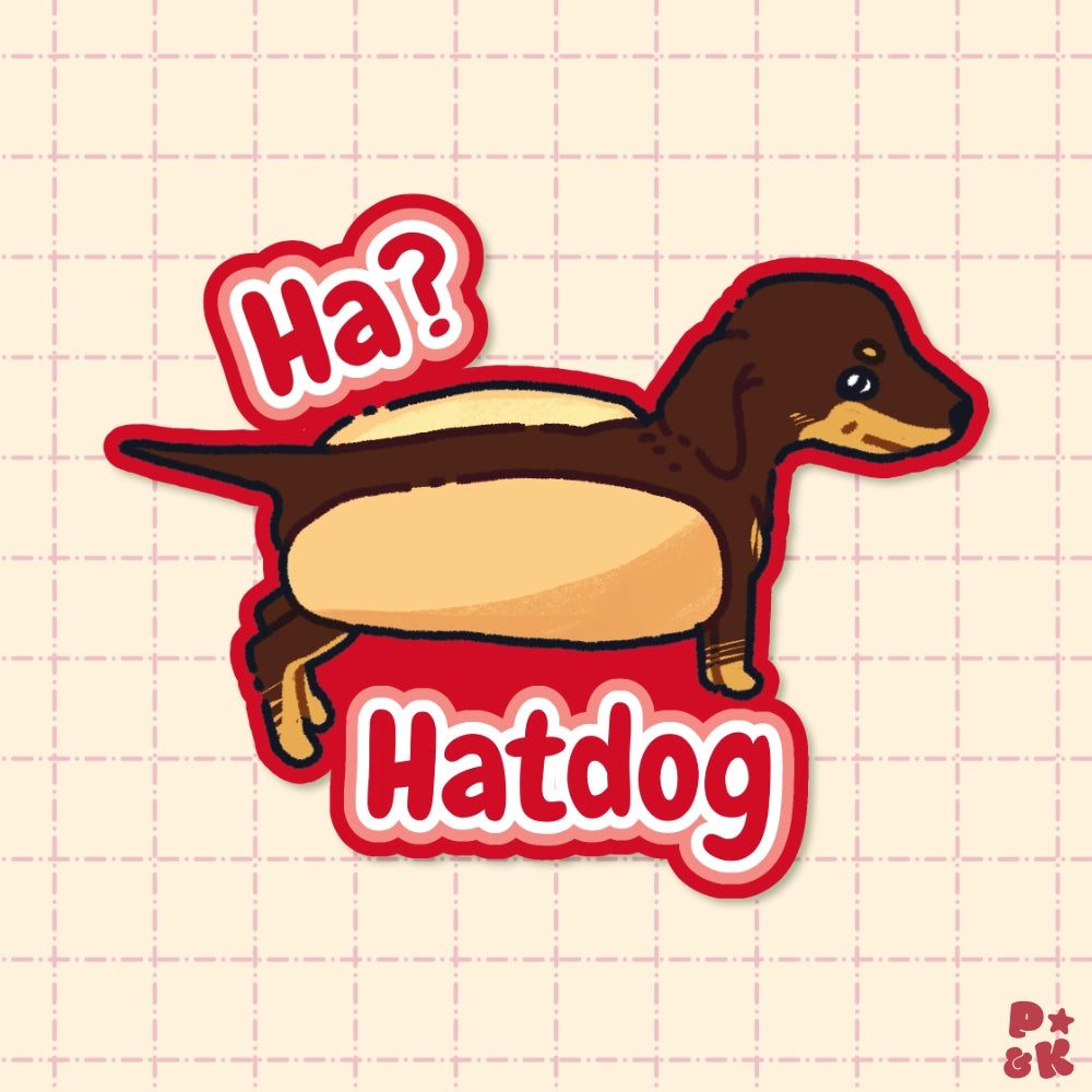A die-cut sticker featuring a cartoon dachshund wearing a hotdog bun, with the text 'Ha? Hatdog' in red and white bubble letters, shown on a pale pink grid background.